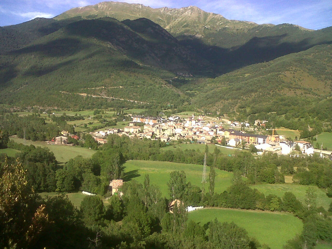 Vista aérea panorámica del pueblo de Vilaller rodeado de prados verdes y montañas
